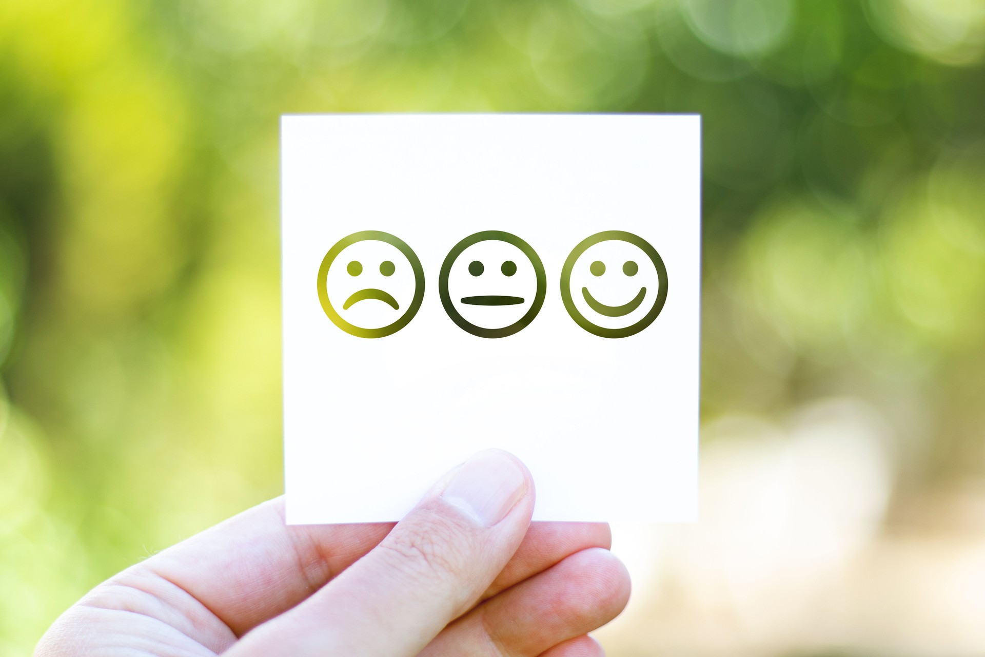 Holding the paper with Emoji Faces in front of a beautiful blur nature background